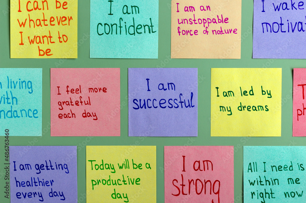 Positive affirmations for every day - words on multi-colored sheets for notes on a green background. Motivational concept with handwritten text.